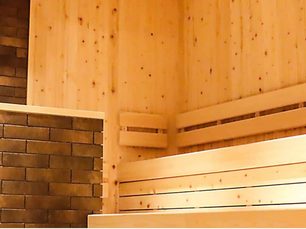 A wooden sauna with benches and a brick wall.