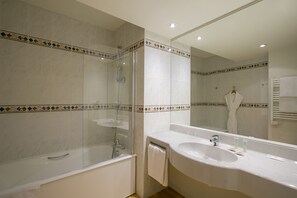 Bathroom features a glass-enclosed shower, large vanity with sink, and decorative border.