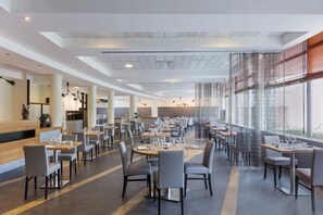 Enjoy meals in a stylish dining area with tables set for guests, surrounded by a contemporary aesthetic.