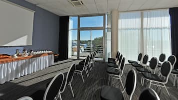 A conference room with a long table, chairs, a projector screen, and large windows.