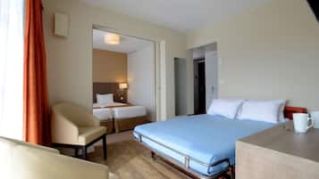A hotel room with a bed, a chair, a desk, and a small table.