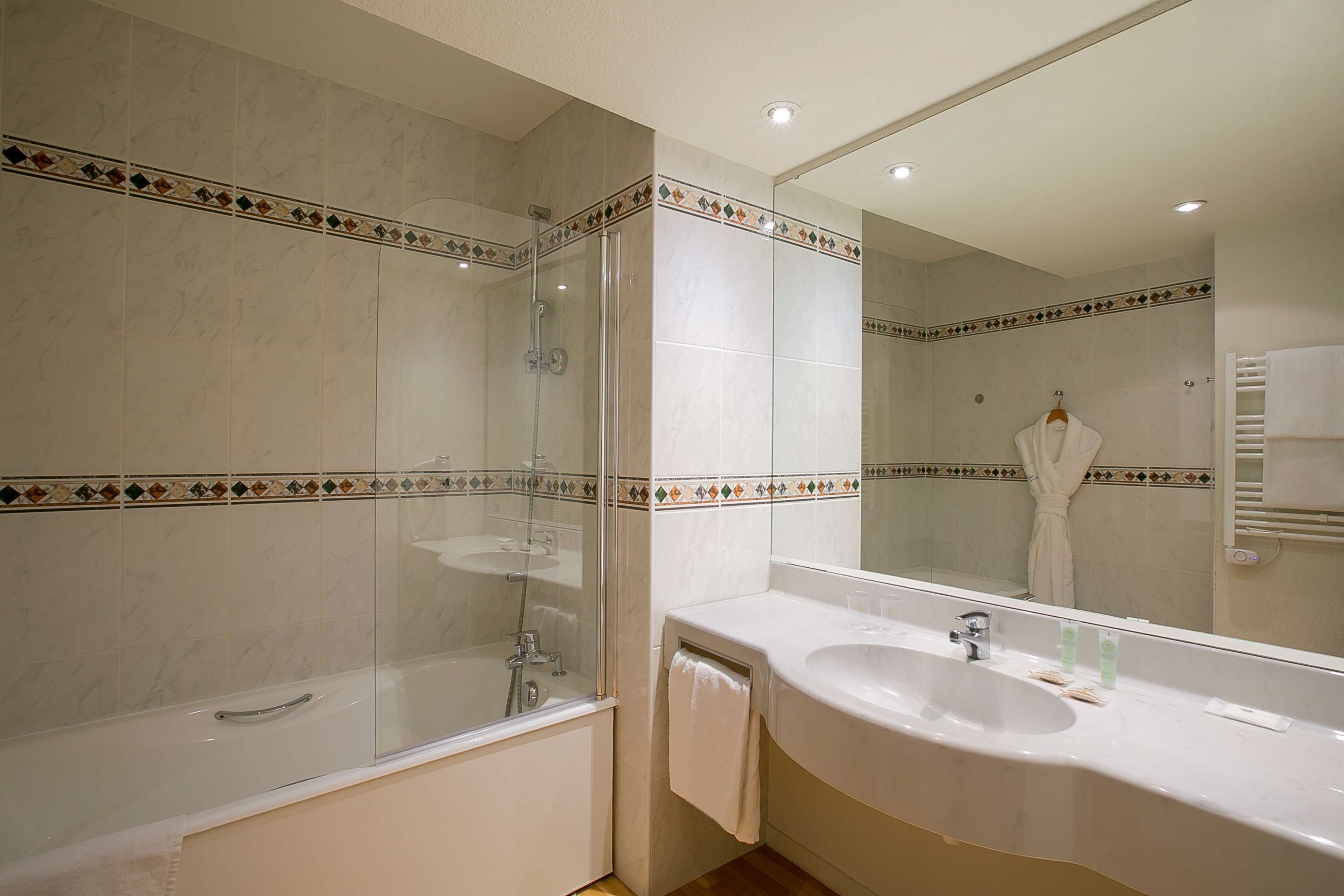 A modern bathroom with a glass-enclosed shower, a large sink, and a mirror.