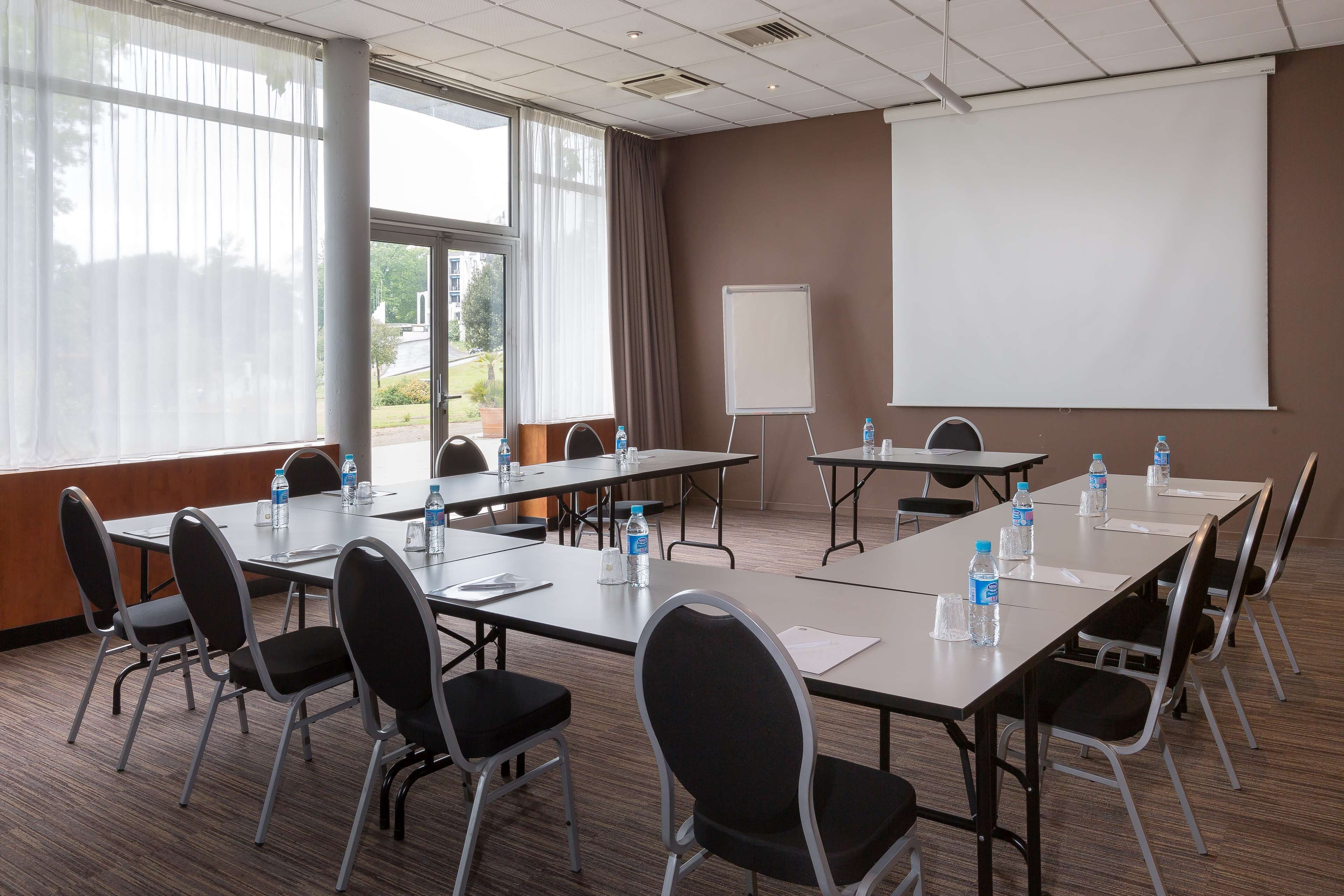A conference room with a large table, chairs, a projector screen, and water bottles.
