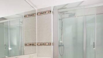 A modern bathroom with a large sink, a glass shower enclosure, and a mirror.