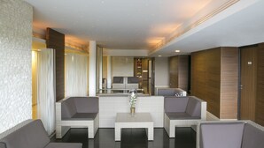 A modern lobby with a seating area, a reception desk, and a mirror reflecting the space. - Best Western Sourceo (Saint-Paul-les-Dax)
