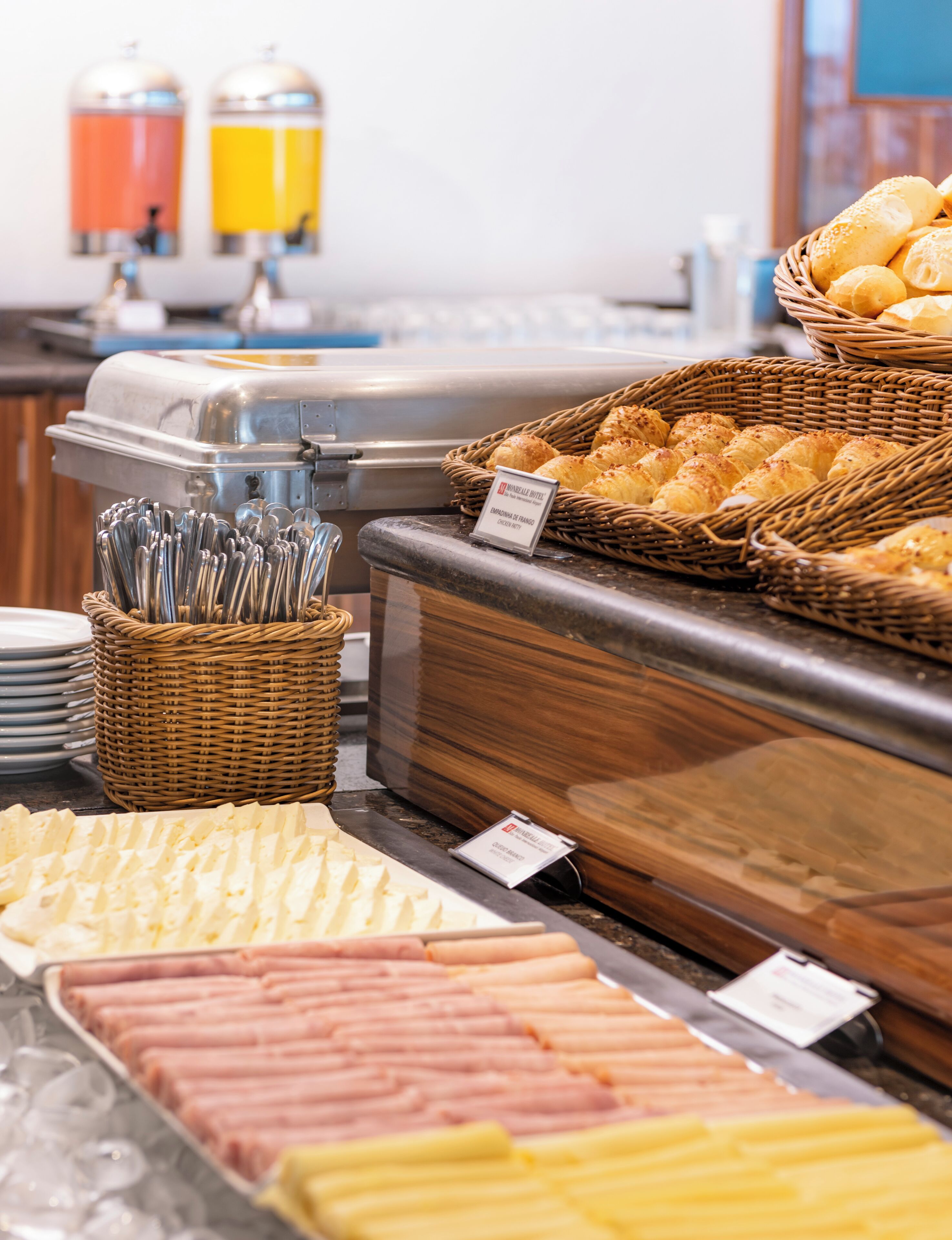 Buffet com diversos alimentos, incluindo pão, doces e carnes.