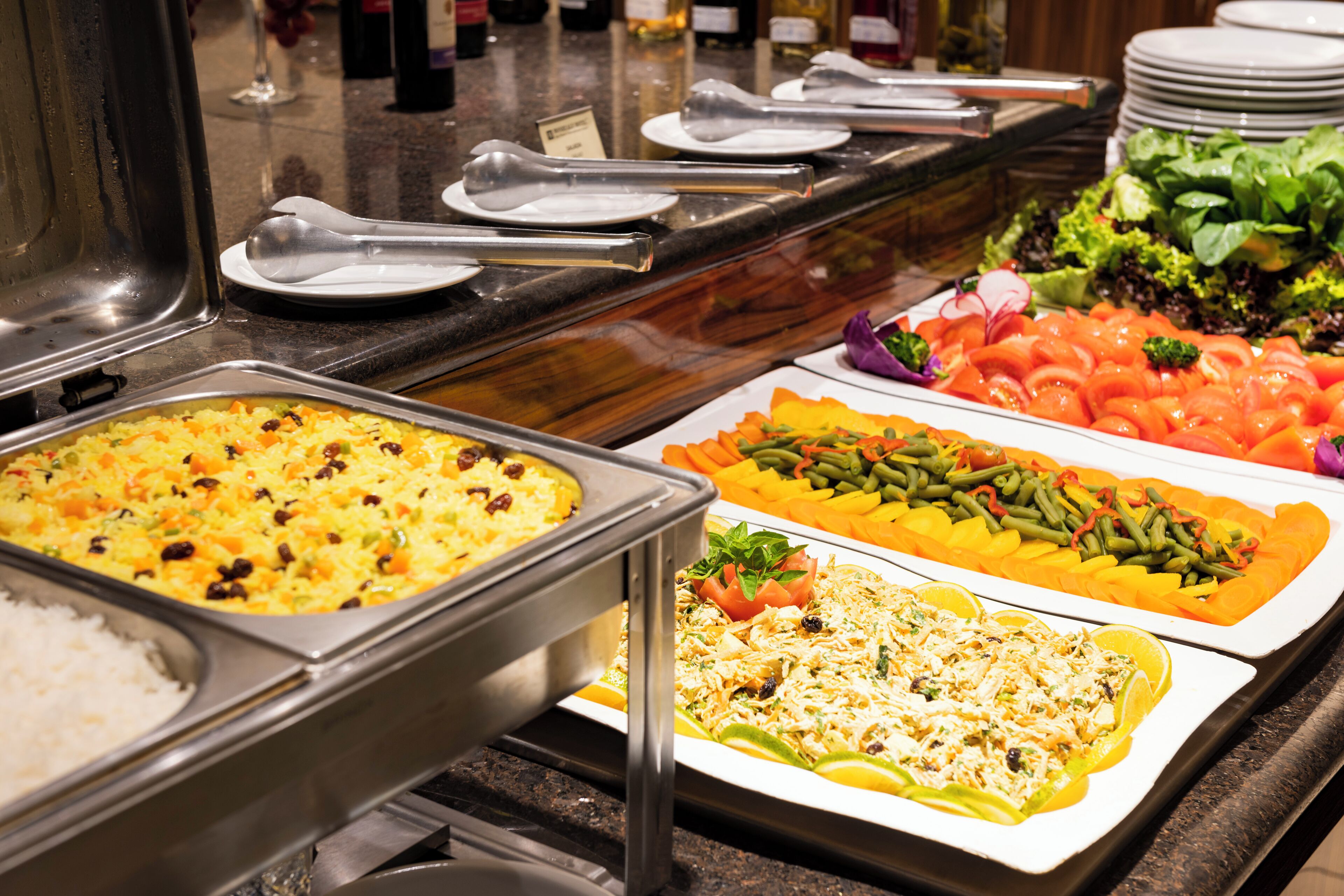 Un bufé con diversos platos, incluyendo arroz, verduras y ensaladas.