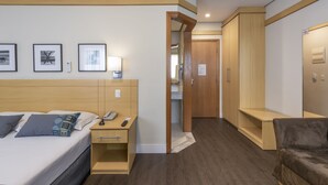 Ein Hotelzimmer mit Bett, Nachttisch, Lampe und einem Holzschrank.