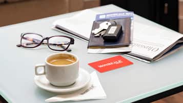 A table with a cup of coffee, a pair of glasses, a magazine, a key, and a red card.
