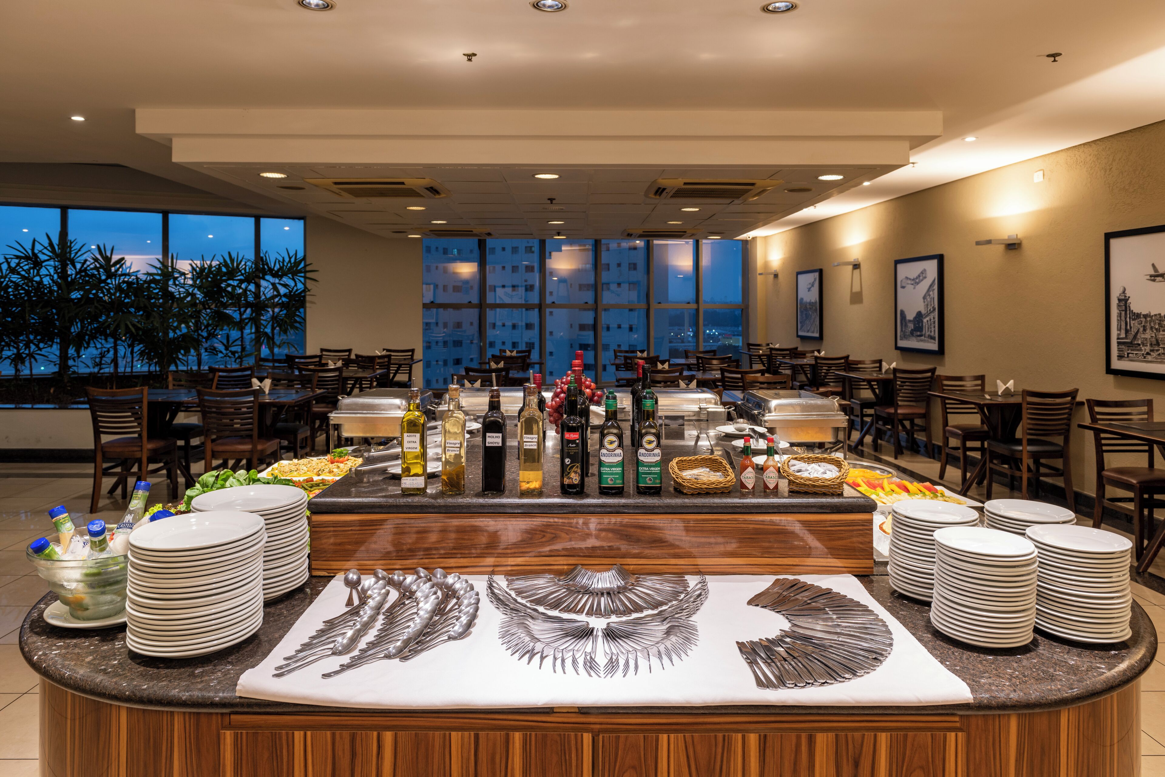 A buffet setup with various food items, a large decorative centerpiece, and a view of the cityscape through large windows.