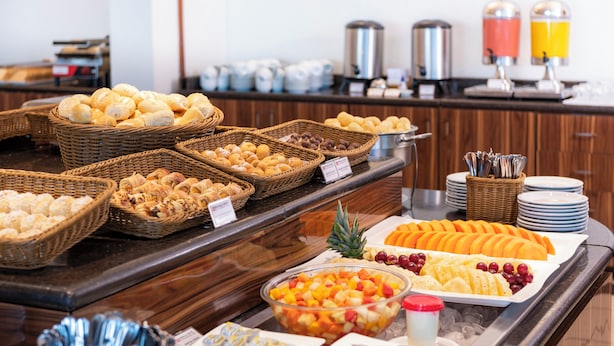 Ein Buffet mit verschiedenen Speisen, darunter Brot, Gebäck, Obst und Soßen.