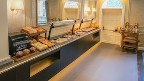 Un'area buffet con diverse opzioni di cibo, una macchina per caffè e un distributore di succo di frutta.
