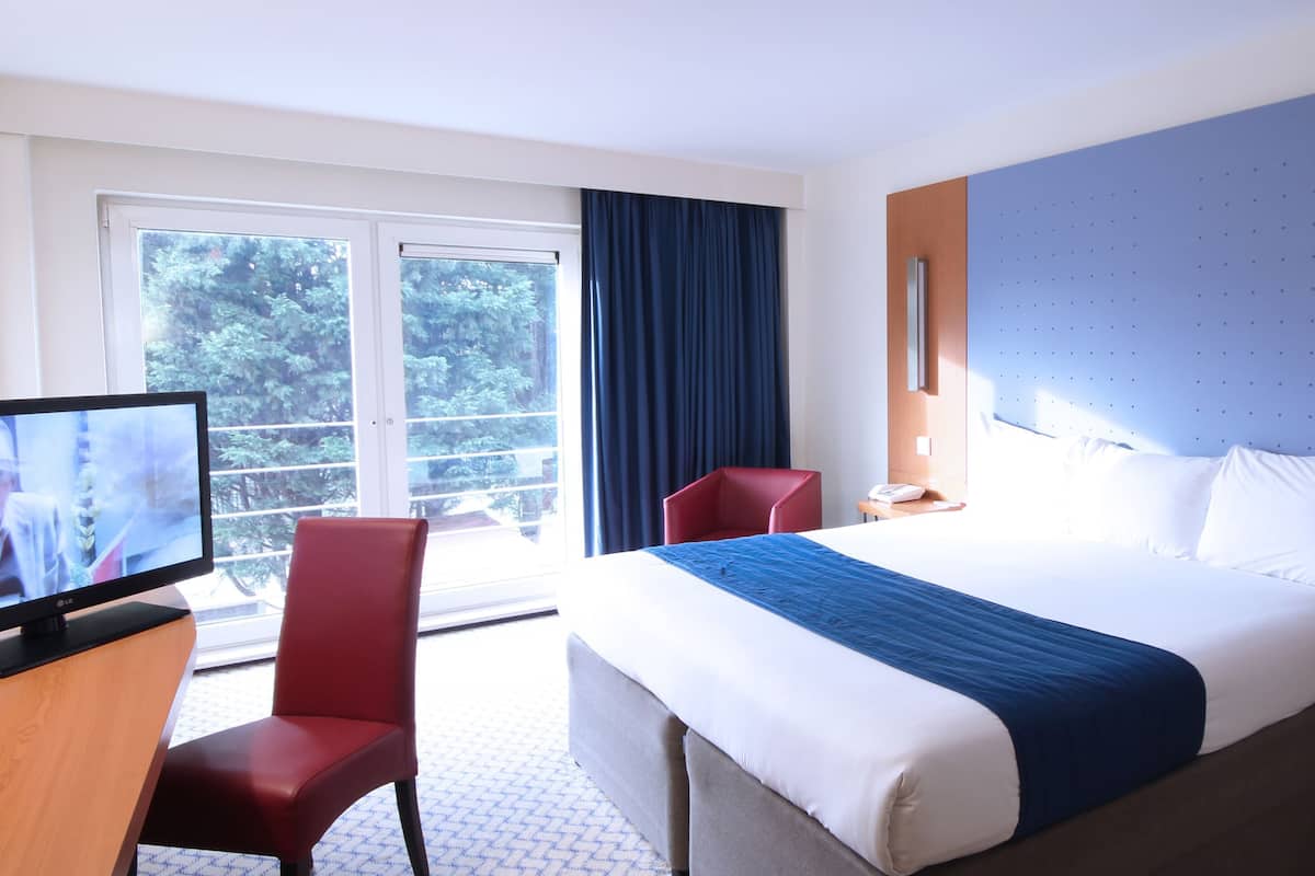 A hotel room with a bed, a television, a desk, and a chair.