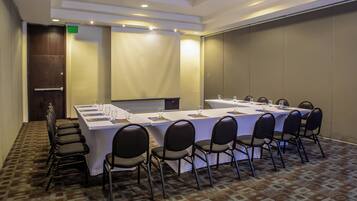 A conference room with a long table, black chairs, and a carpeted floor.
