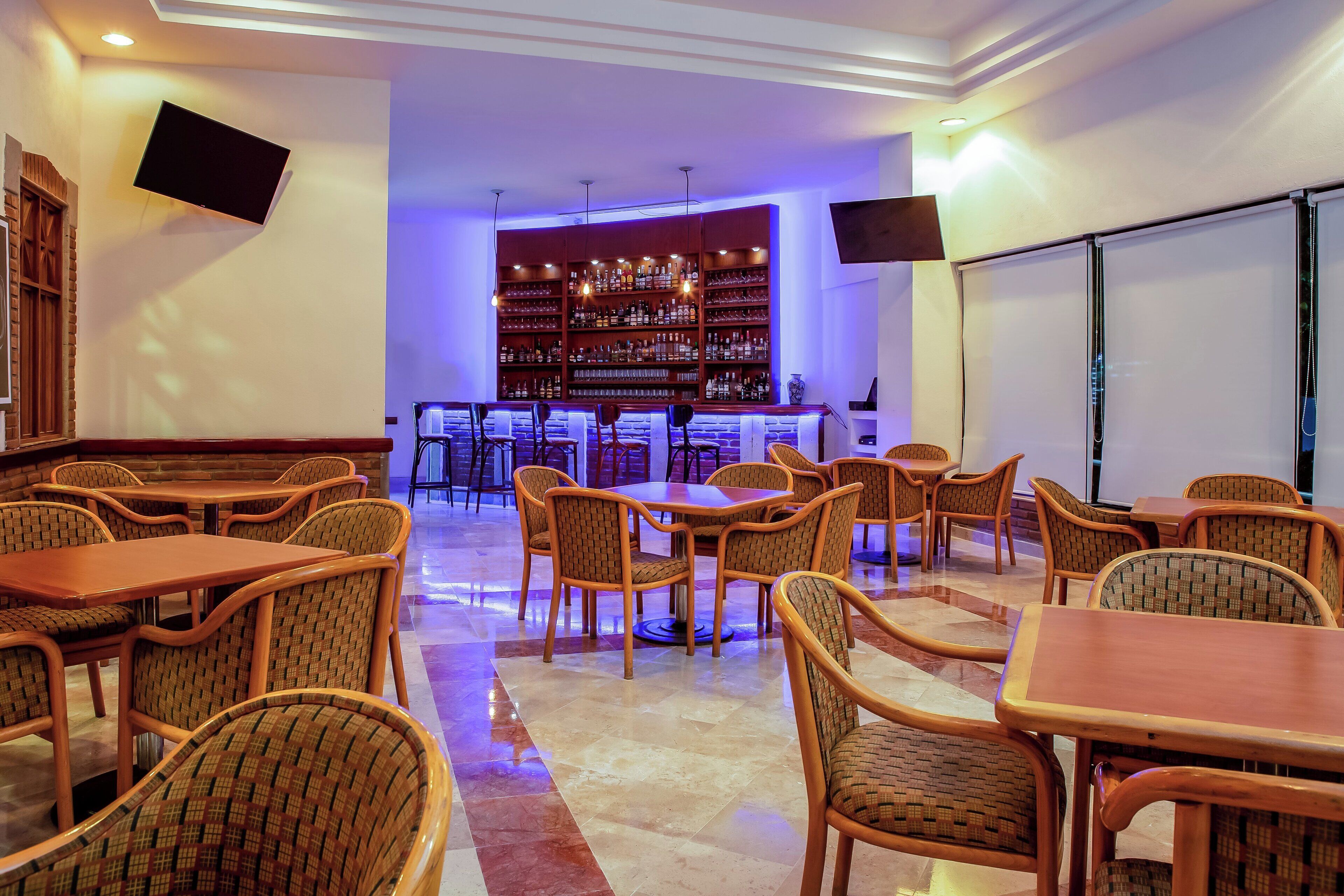 A hotel lobby with multiple seating areas, a bar, and a large screen.