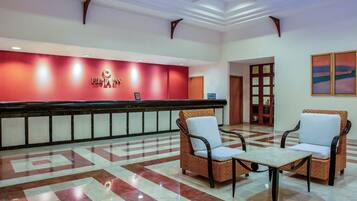 A reception area with a red wall, a reception desk, and two wicker chairs with white cushions.