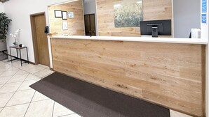 A reception desk with a wooden finish, a black printer, and framed certificates on the wall.