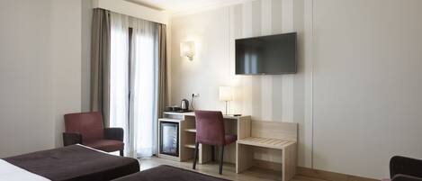 A hotel room with two beds, a desk with a computer, a TV, and a window with curtains.