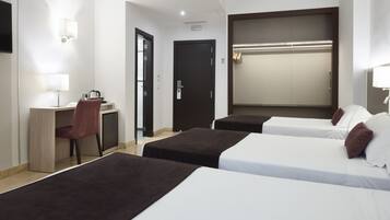 A hotel room with two single beds, a desk with a chair, a TV, and a wardrobe.