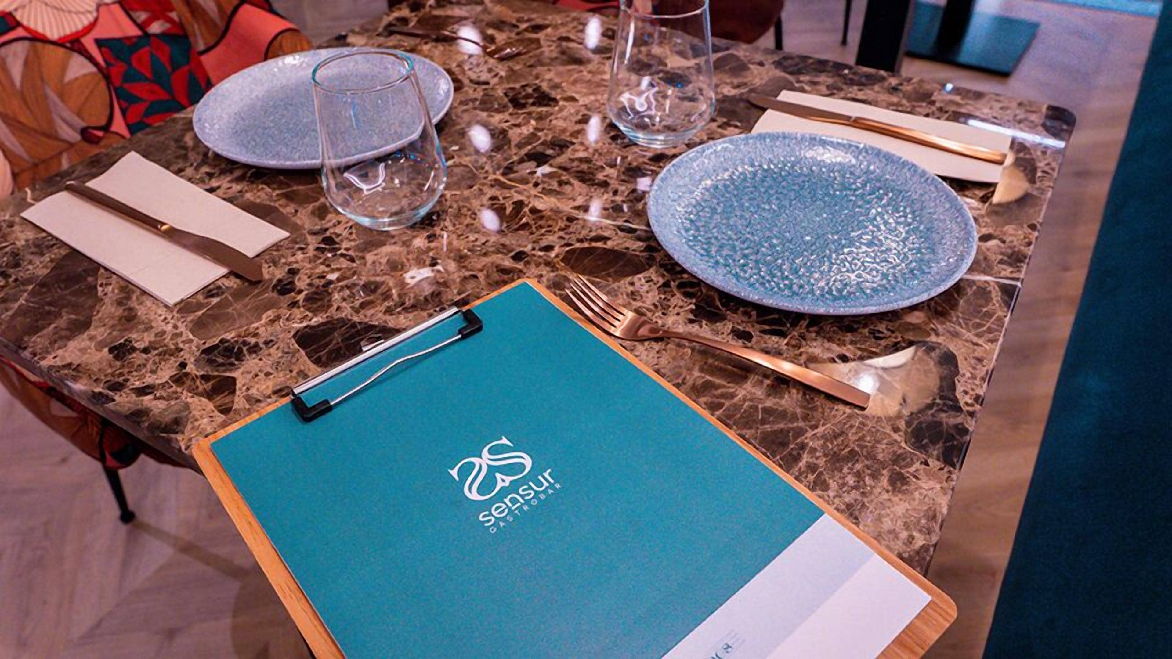 A table set with plates, cutlery, and a menu.