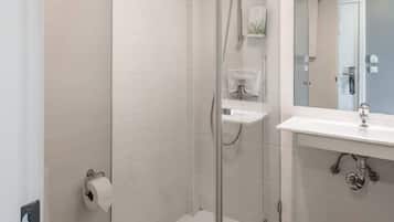 A modern bathroom with a glass-enclosed shower, a toilet, and a sink with a mirror.