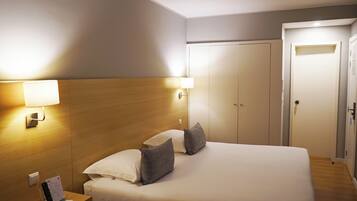 Una habitación de hotel con una cama, mesita de noche y armario.