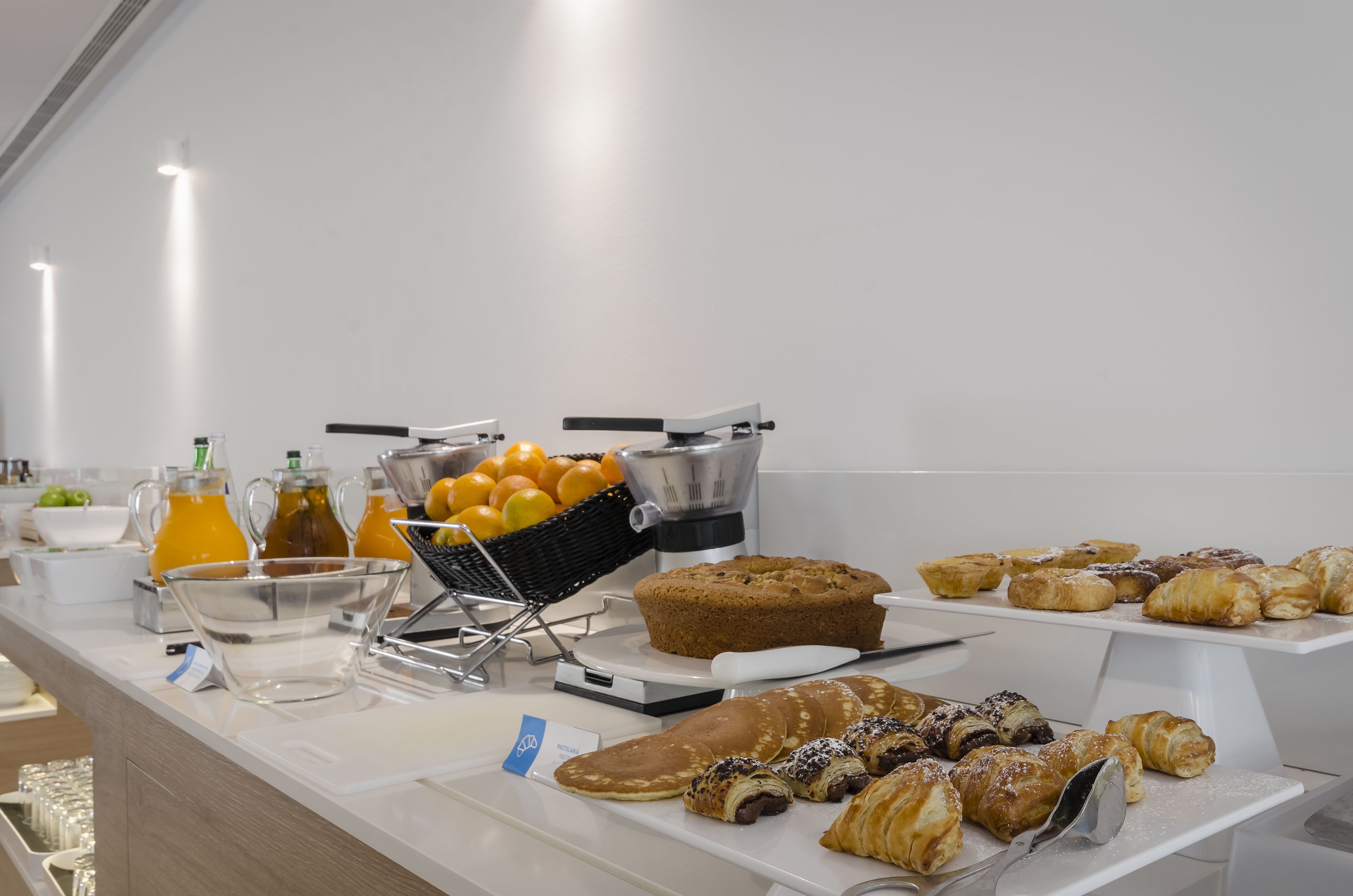 Un buffet proposant divers articles pour le petit-déjeuner, notamment des viennoiseries, des fruits et des boissons.