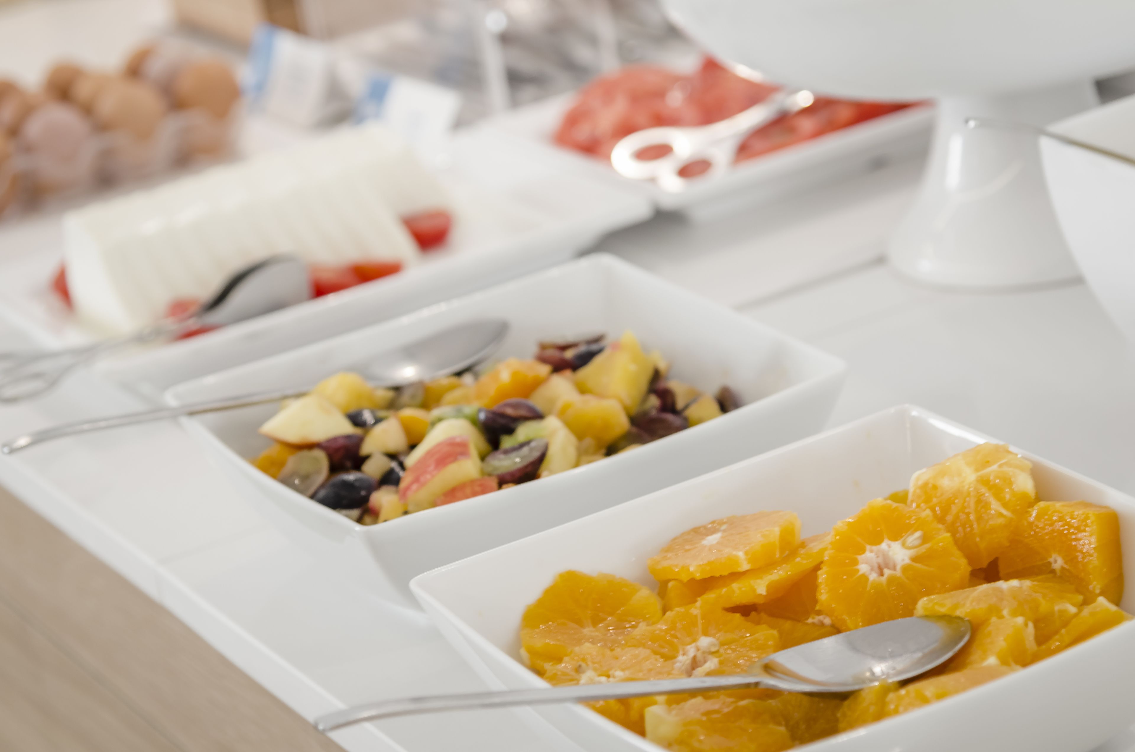 A breakfast buffet with various fruit options and utensils.