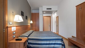 A hotel room with a large bed, bedside lamps, a wooden wardrobe, and a desk with a telephone. - Piccolo Verona (Verona)