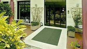 A building with a green mat at the entrance, potted plants, and a door leading inside. - Piccolo Verona (Verona)