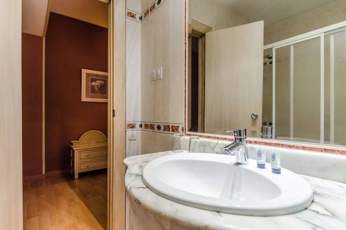 Un baño con lavamanos de mármol, un espejo y un mueble de madera.