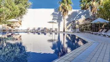 Una piscina al aire libre de temporada, sombrillas