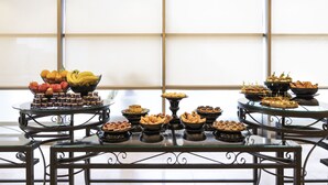 Una mesa de buffet con diversos alimentos y un cuenco de frutas.