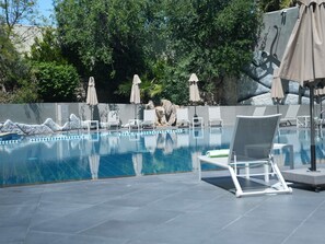 Una piscina al aire libre de temporada, sombrillas