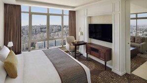 Habitación de hotel con una cama grande, un escritorio, una televisión y vistas a la ciudad.