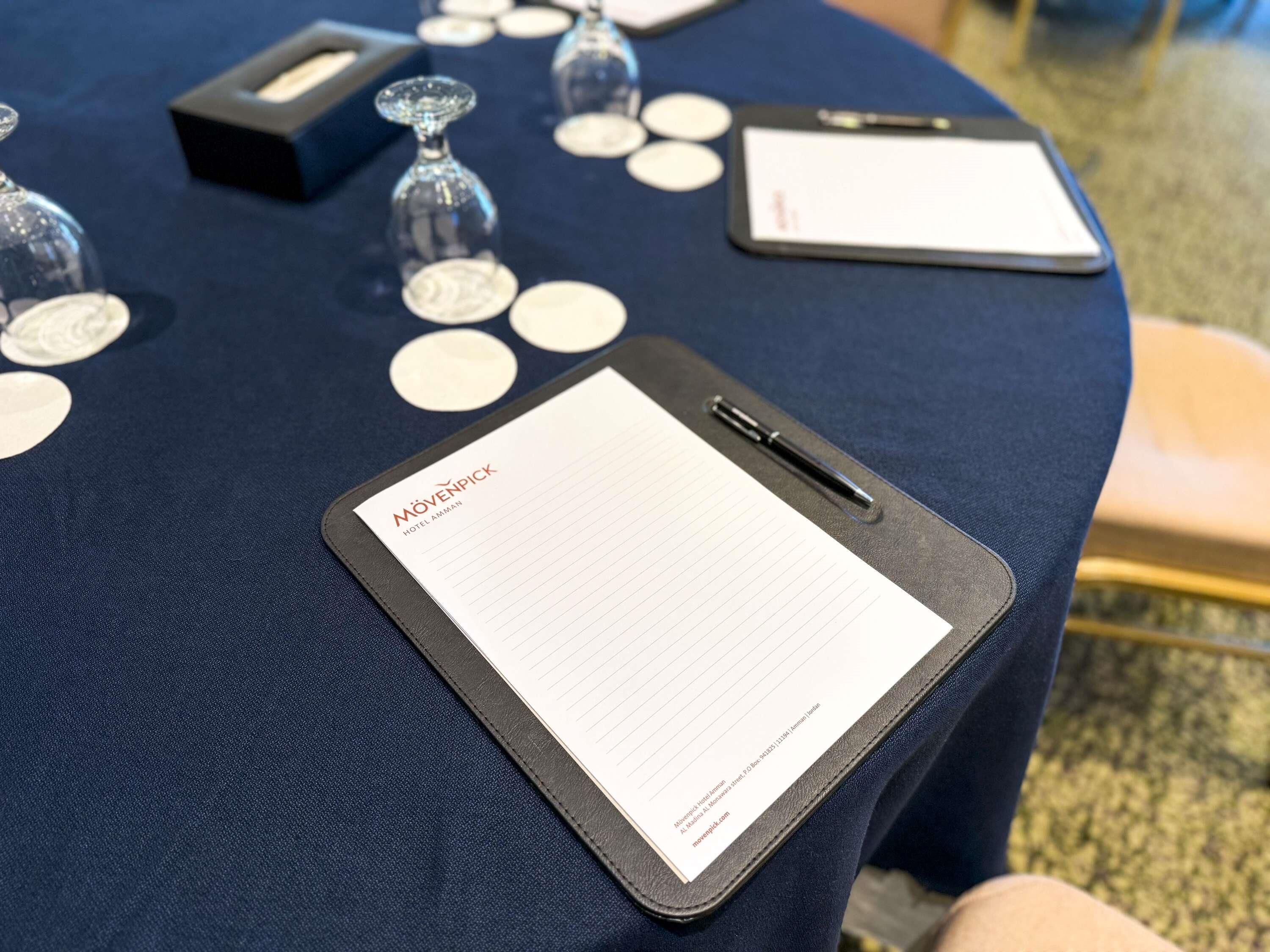 A table with a clipboard, name tags, and a pen.