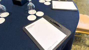 A table with a clipboard, name tags, and a pen.
