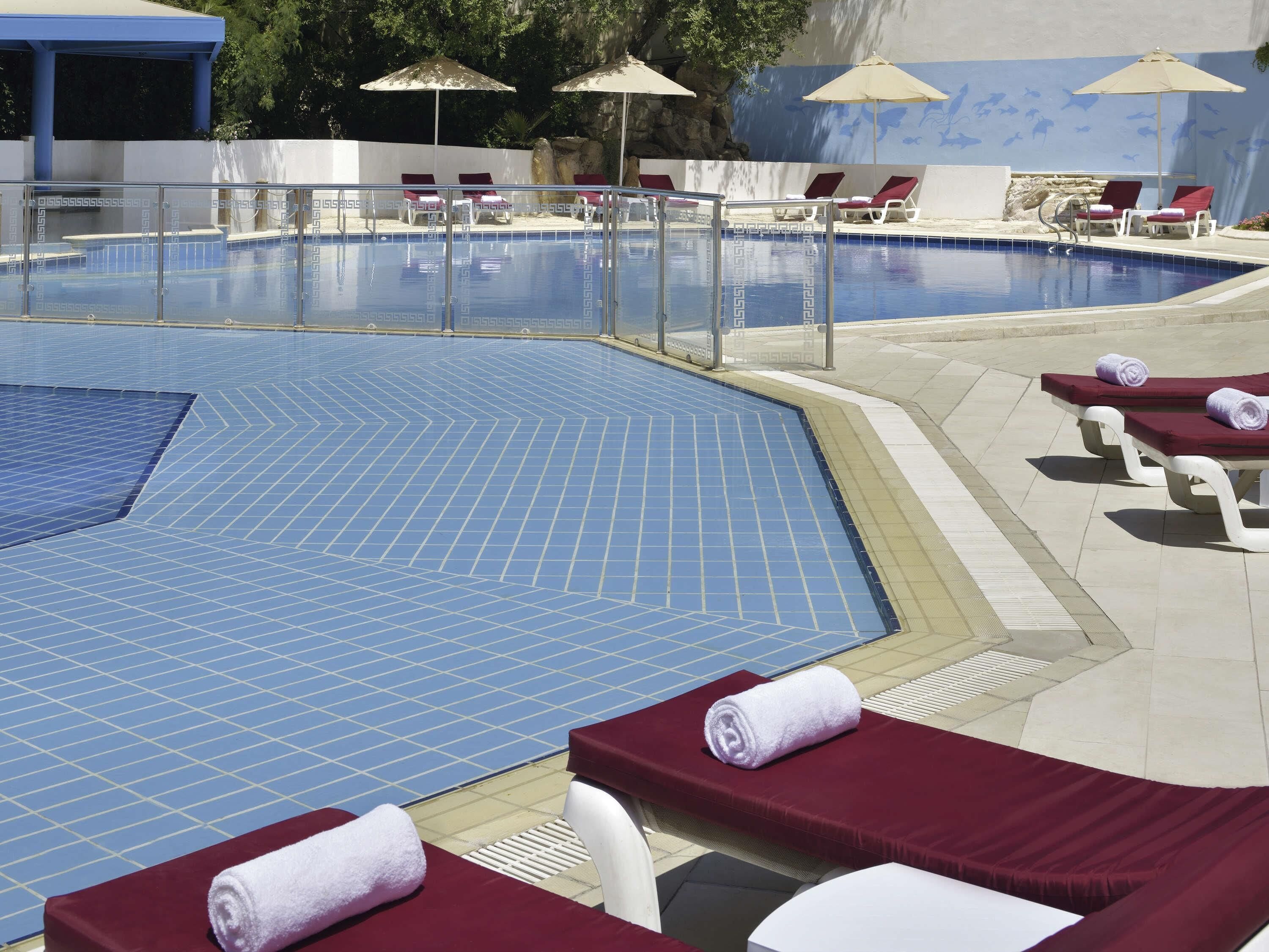 Una piscina con sillones de descanso y sombrillas.