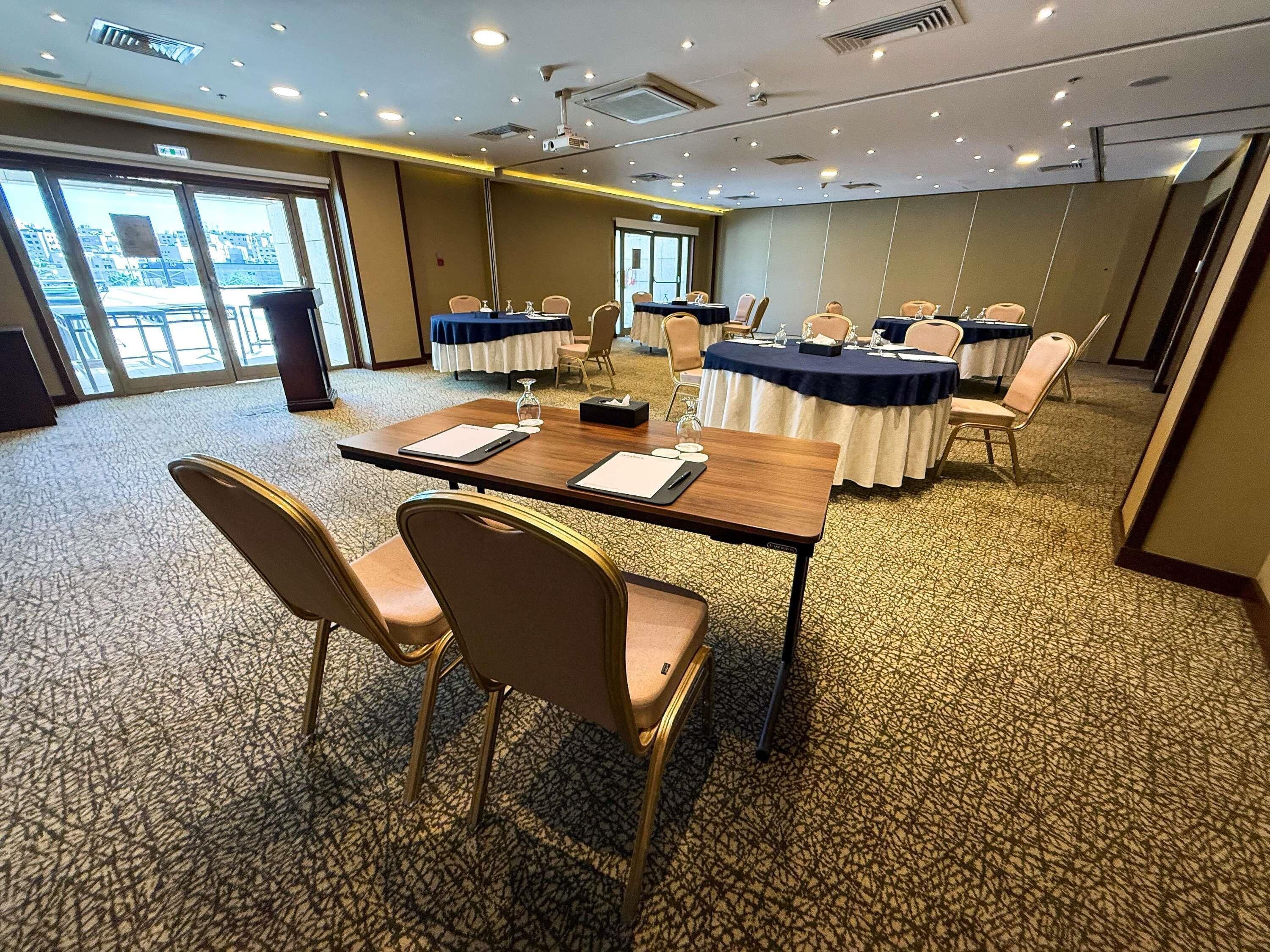 A conference room with tables, chairs, and a projector.