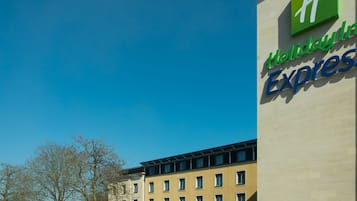 Un hotel con un llamativo letrero de 'Holiday Inn Express', una fachada de edificio moderna y un cielo azul despejado.