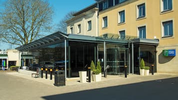 Un hotel moderno con entrada de vidrio, asientos exteriores y un letrero de Holiday Inn Express.