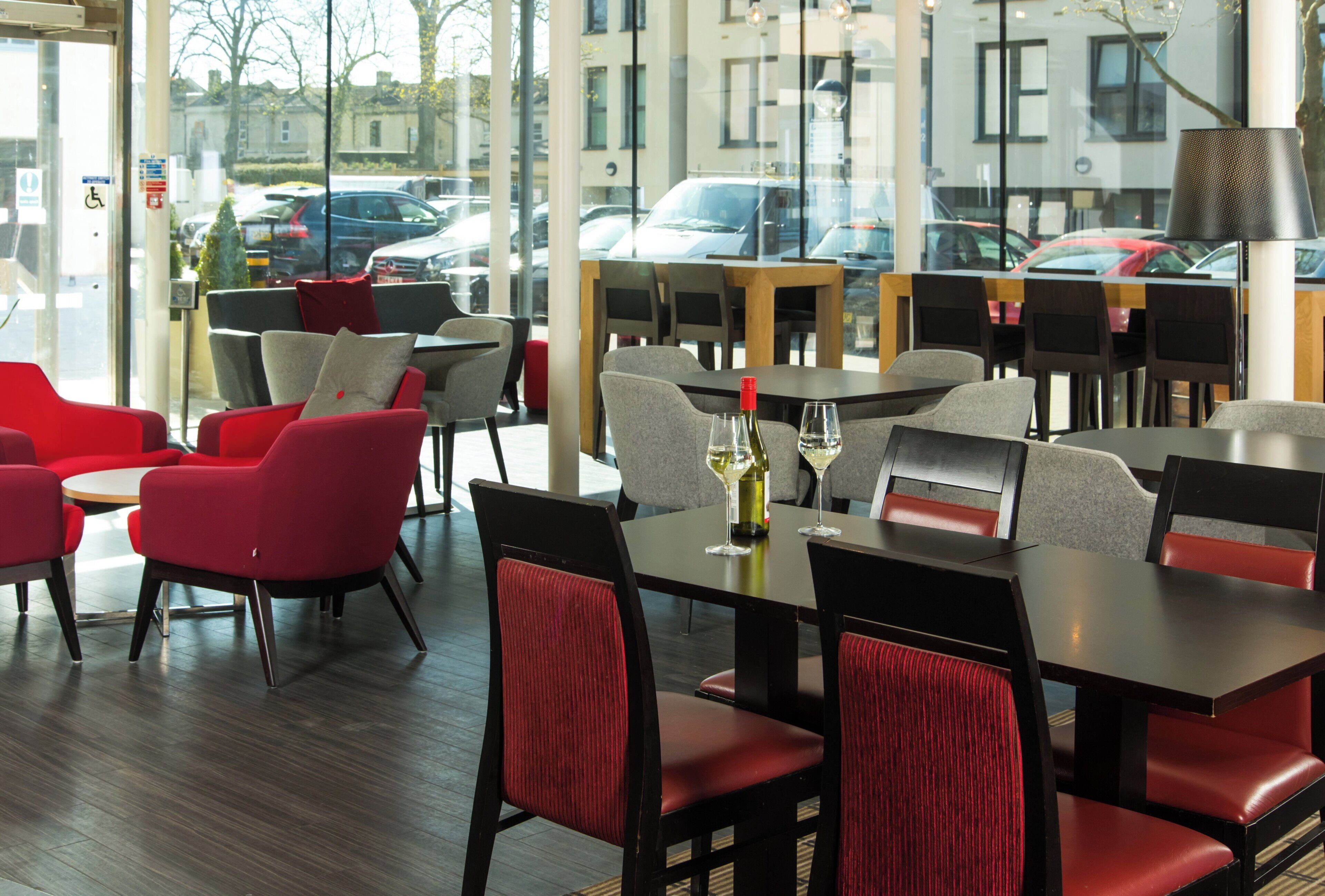 A restaurant with tables and chairs, a bottle of wine, and a glass on one table.