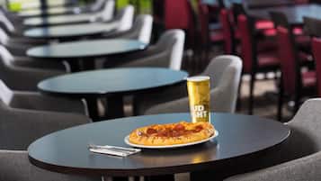 Una mesa con pizza y una lata de Bud Light, rodeada de sillas y mesas en un restaurante.
