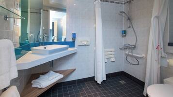 A modern bathroom with a white sink, mirror, and shower.