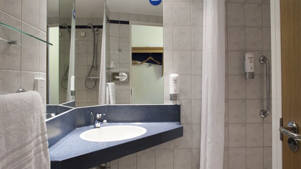Une salle de bain équipée d’un lavabo, d’un miroir, d’une douche et de toilettes.