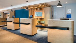 A reception area with wooden reception desks, a blue wall, and a sign for Holiday Inn Express.