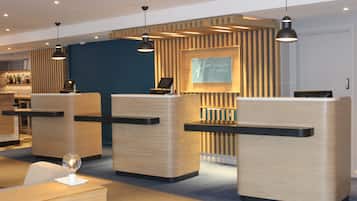 A hotel reception area with wooden reception desks, a blue wall, and a Holiday Inn Express sign.