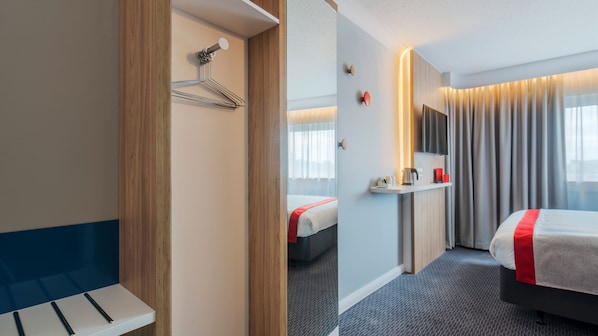 A hotel room with a bed, a bedside table, a mirror, a TV, and a window with curtains. - Holiday Inn Express Oxford-Kassam Stadium by IHG (Oxford)
