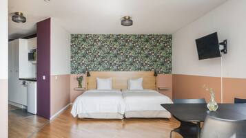 Ein Schlafzimmer mit einem Doppelbett, einem kleinen Tisch mit einer Vase und einem an der Wand befestigten Fernseher.