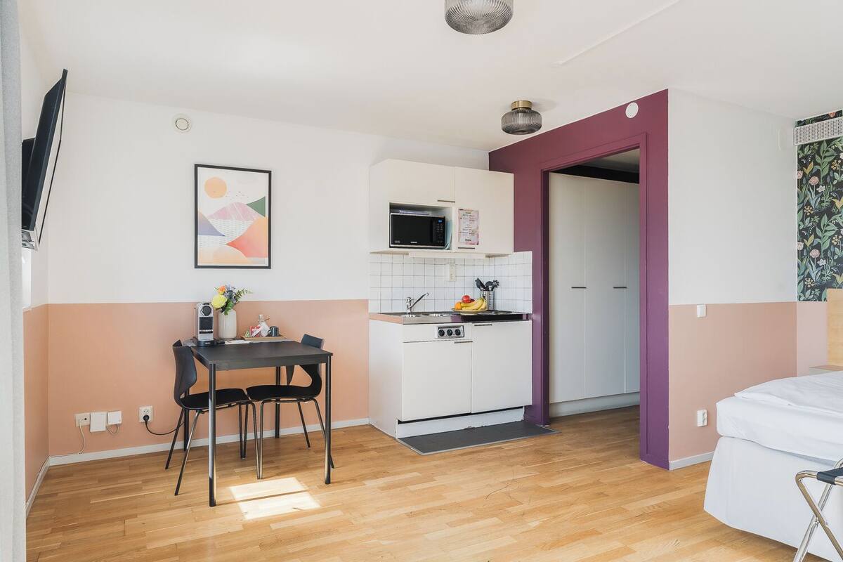 A compact living space with a kitchenette, a dining area, and a bed.